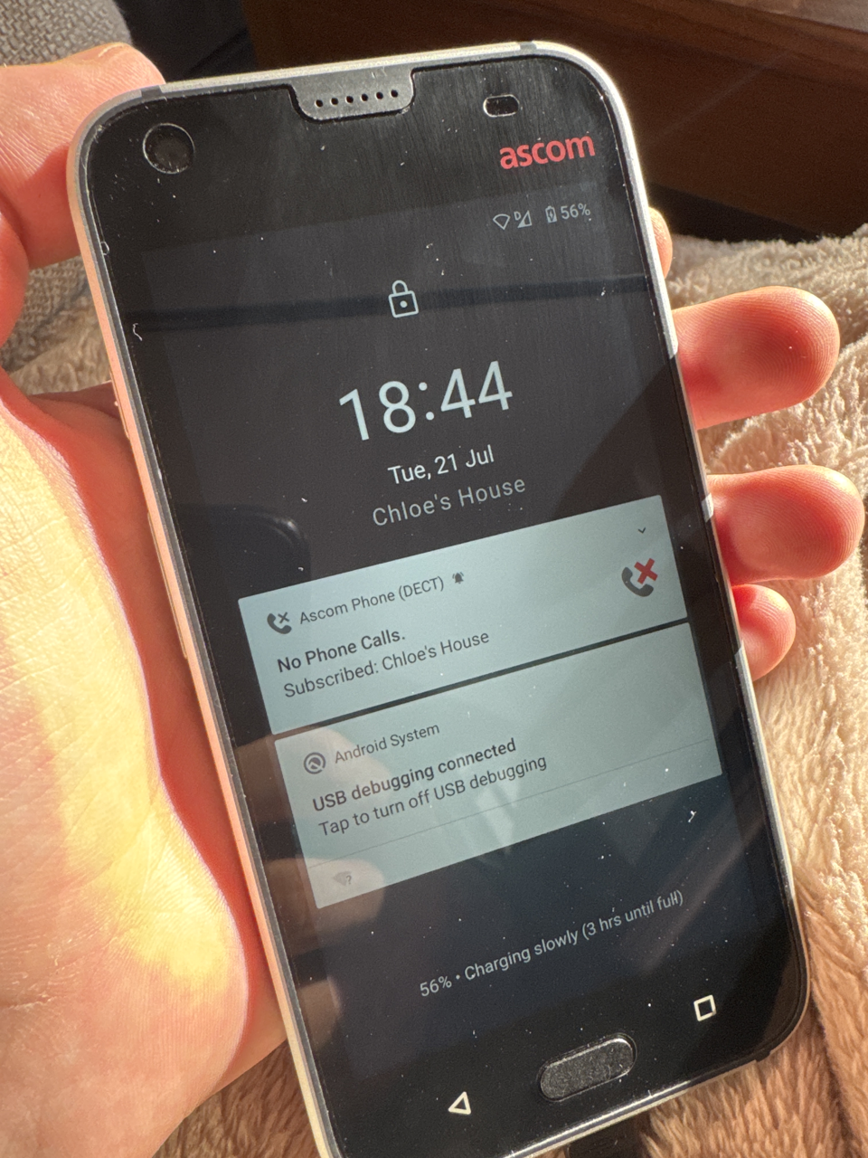 A locked android phone, showing several notifications: - Ascom Phone (DECT): No Phone Calls. Subscribed: Chloe's House - Android System: USB debugging connected